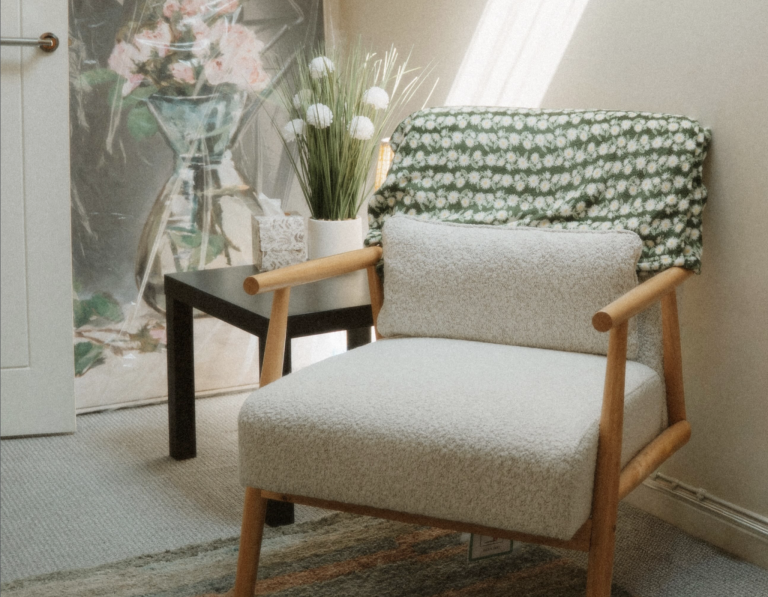 Two chairs and a coffee table with flowers. A therapy room.. Two Ercol style arm chairs in a sunny room with a small coffee table and a vase of flowers.